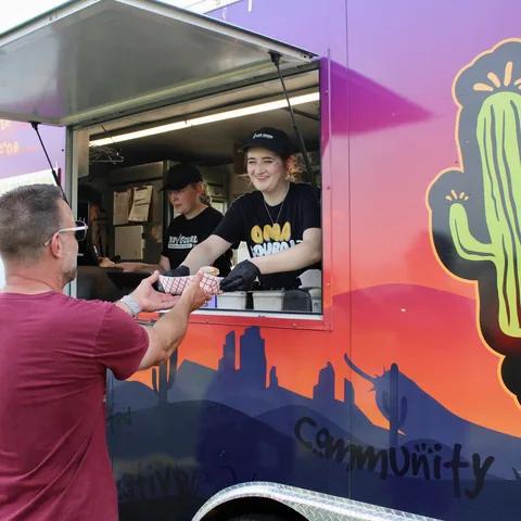 An Oma Gourd crew member handing an order out the truck window to a customer
